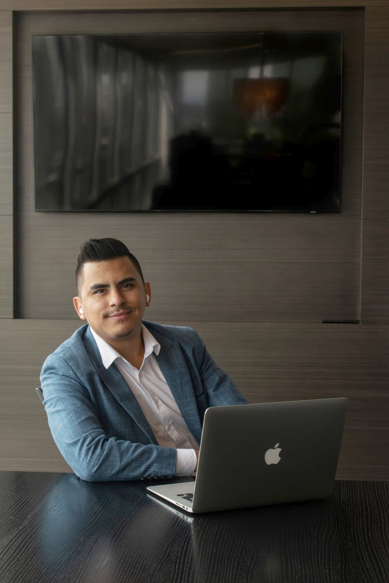 Johan Angel in a blue blazer at a meeting table with his laptop